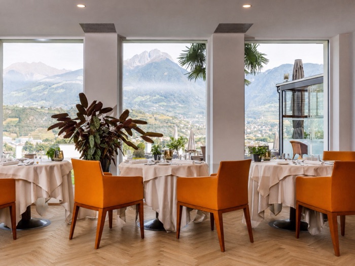 Gedeckte Tische im Speisesaal des Pazeider vor bodentiefen Fenstern mit Blick auf die Berge