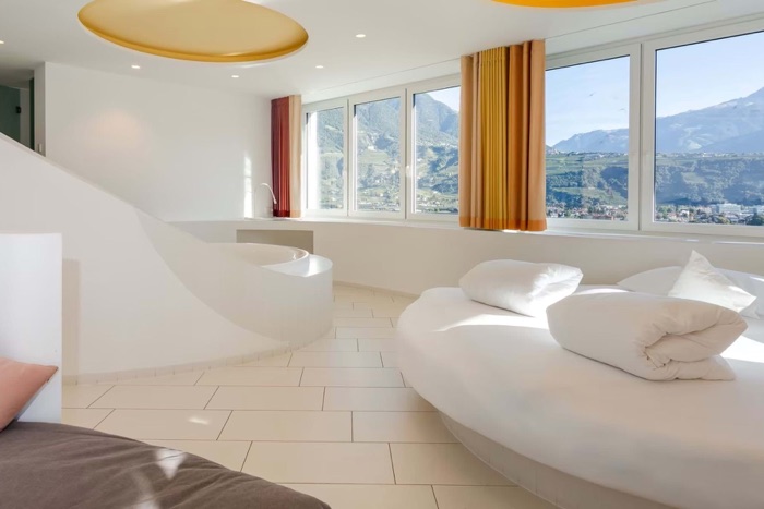 Suite Private SPA im Pazeider mit geschwungener weißer Badewanne, rundem Ruhebett und Panoramafenstern über dem Tal