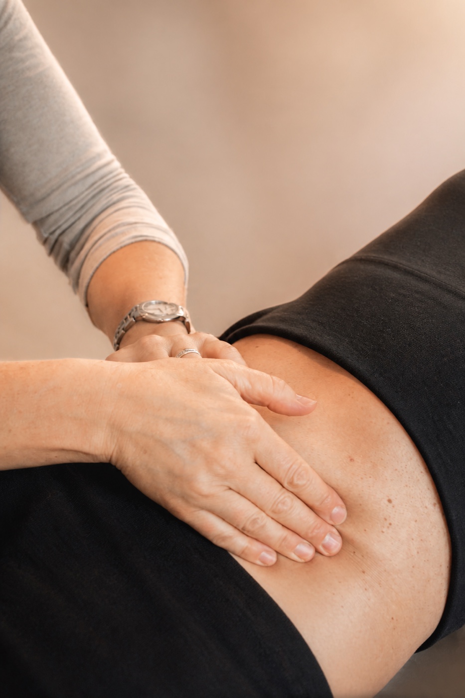 Zwei Hände liegen flach auf dem Bauch einer Frau, die bekleidet auf dem Rücken liegt