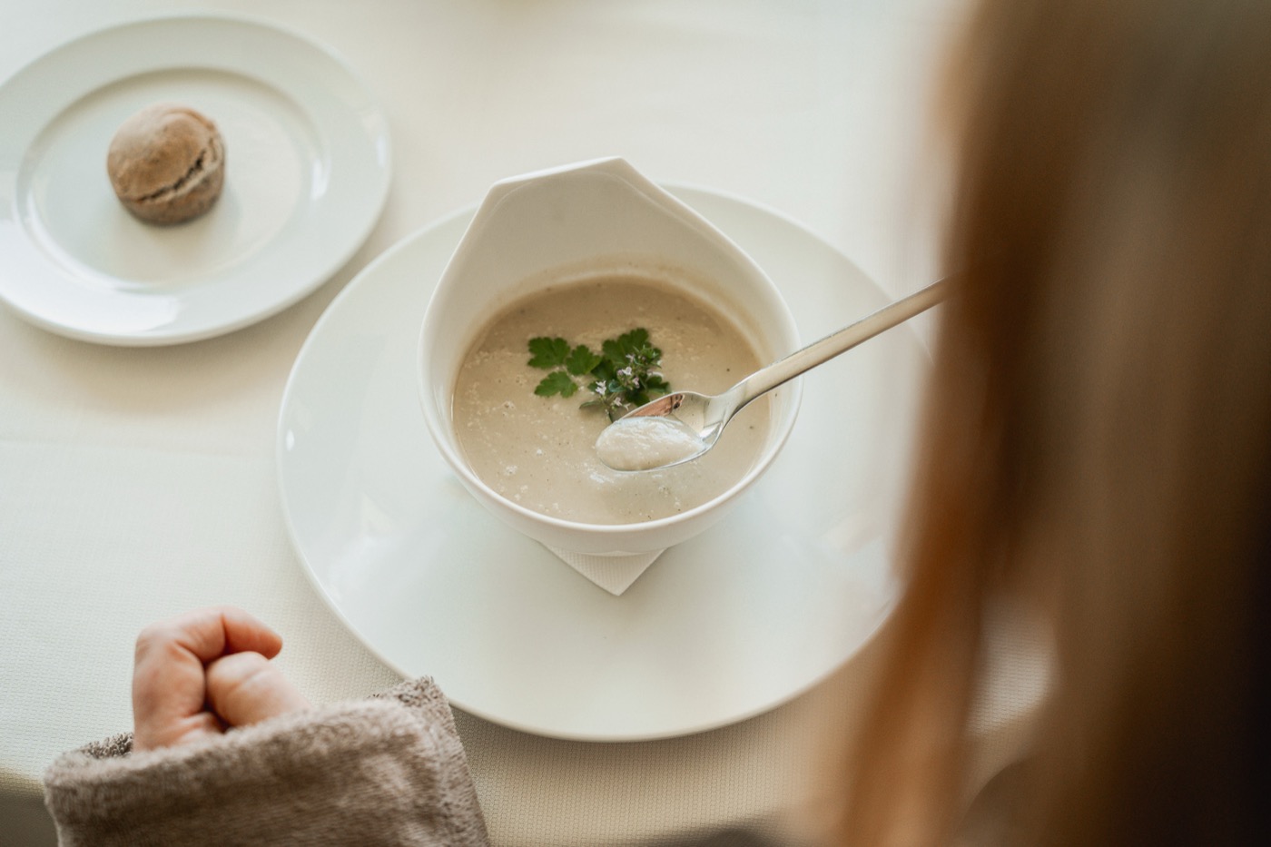 Ein Gast isst eine helle Suppe am gedeckten Tisch